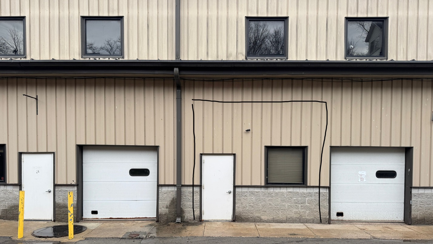 The same elevation before reinvestment, with tan siding and white service doors